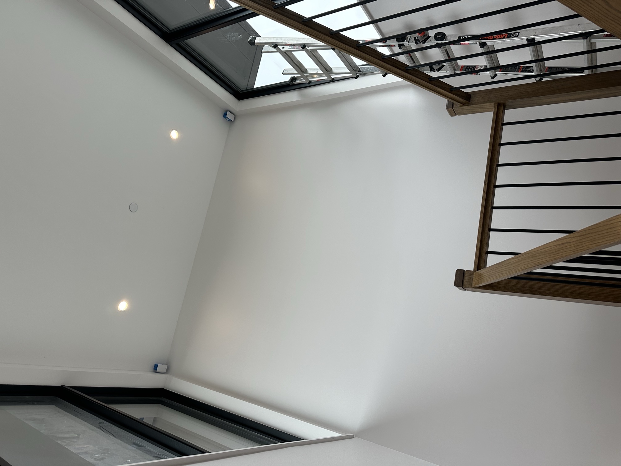 Modern staircase with clean white walls and skylights by J&B Painting
