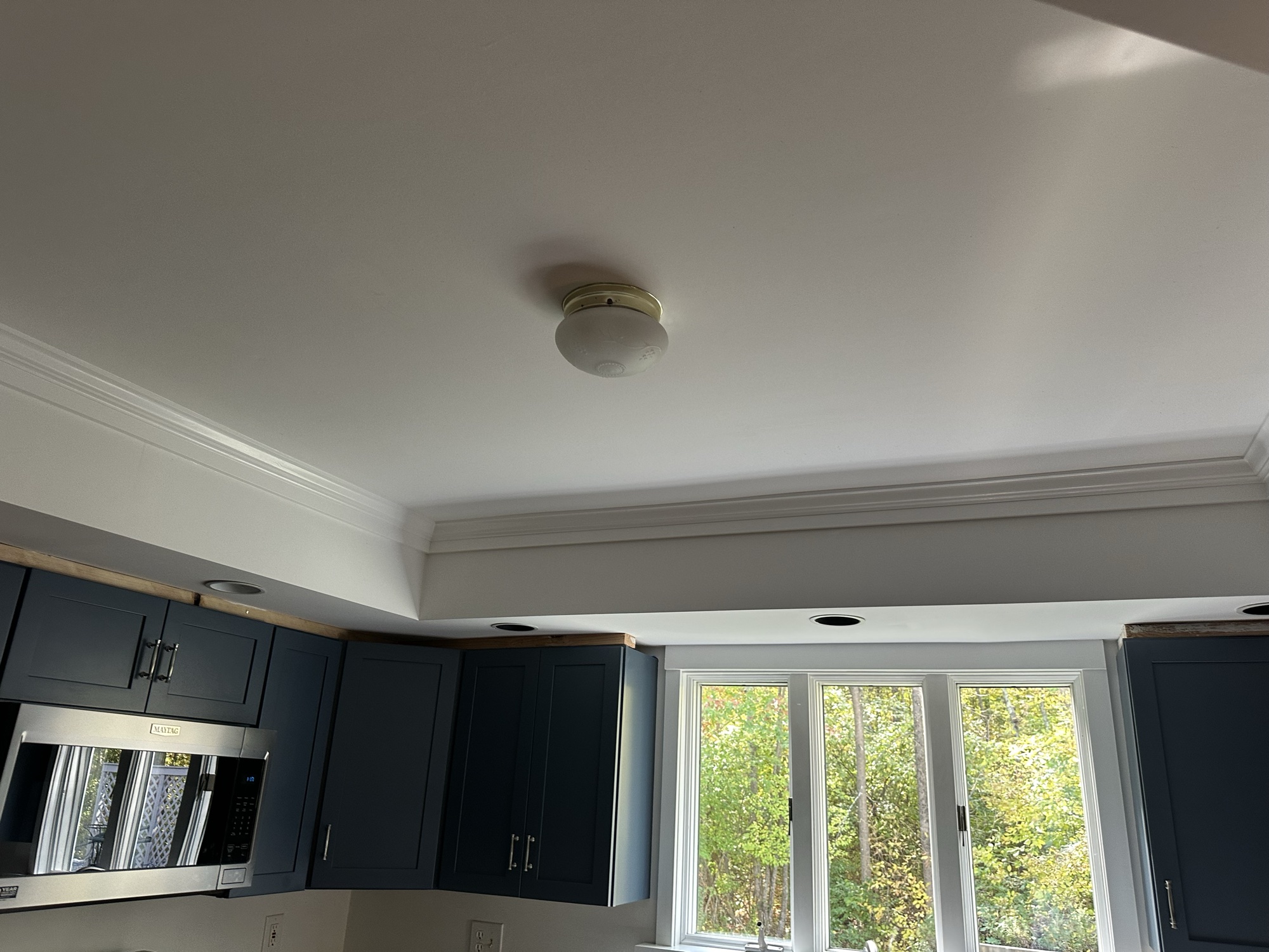 Navy blue upper kitchen cabinets with crown molding by J&B Painting