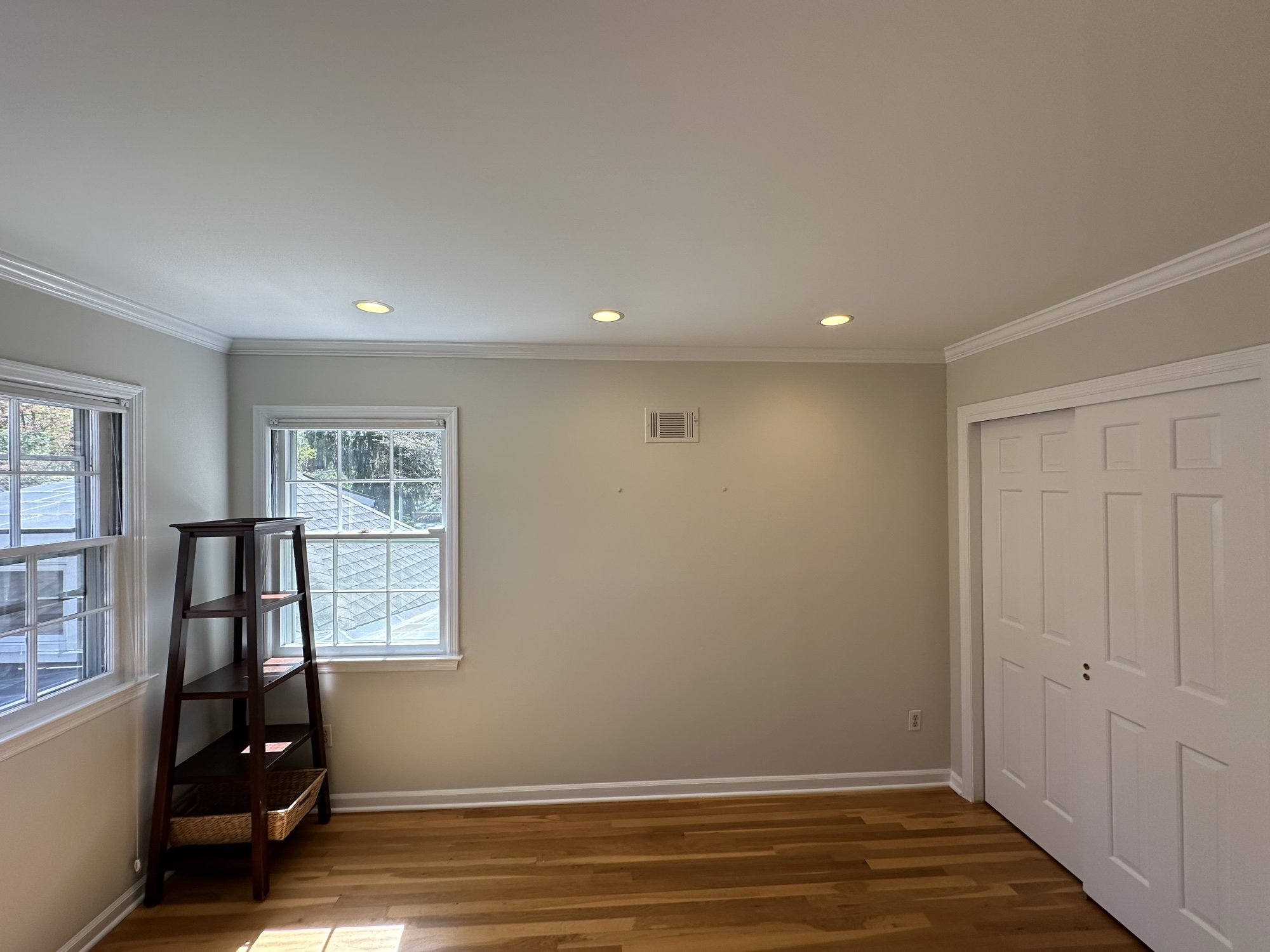 Bedroom with soft gray walls and hardwood floors by J&B Painting