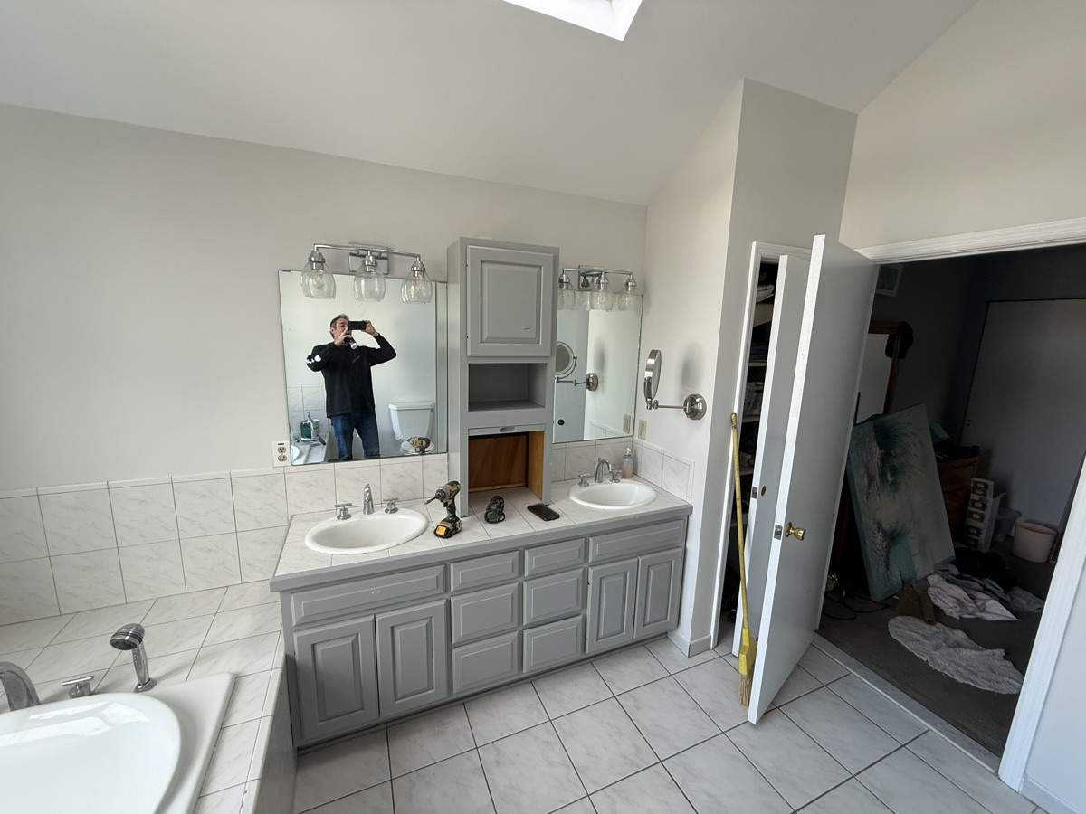 Full bathroom view with gray painted vanity and skylight by J&B Painting