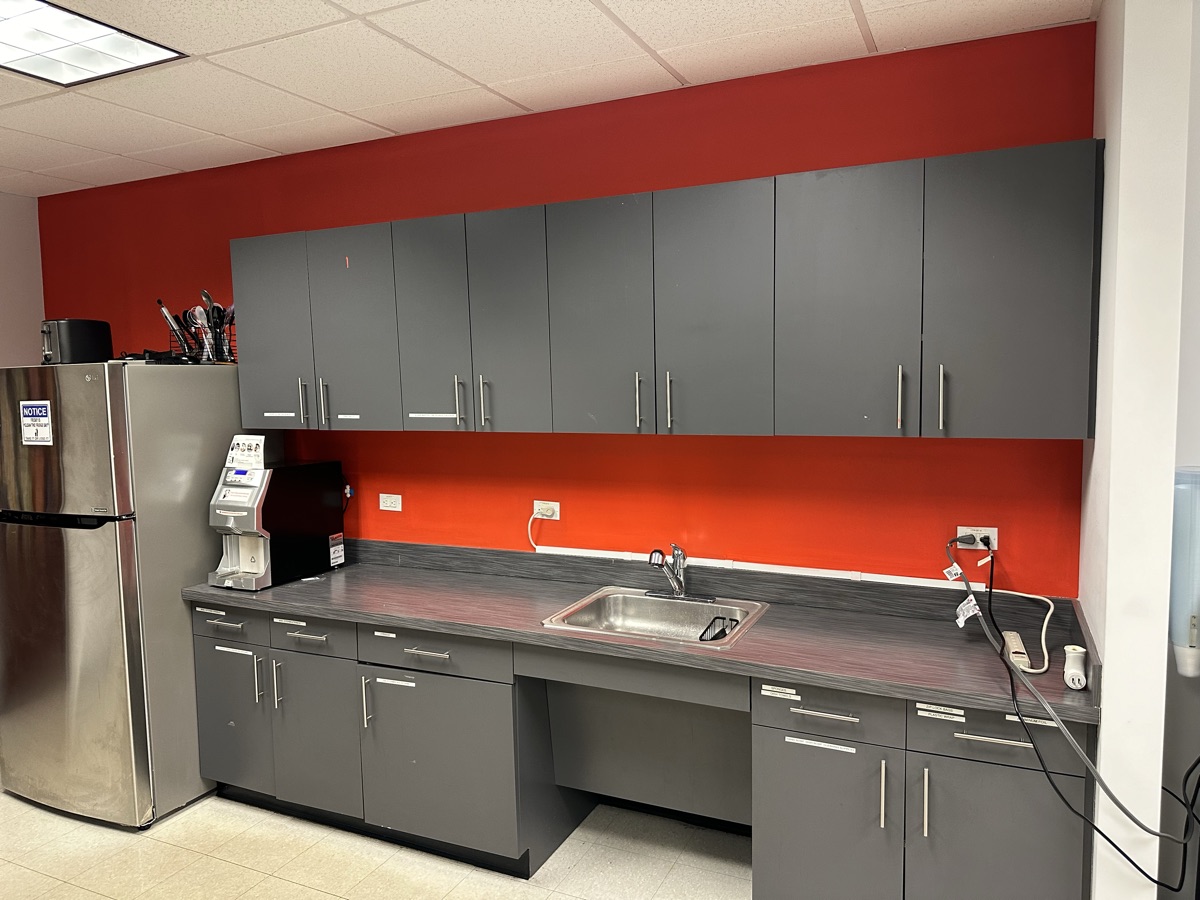 Office kitchenette with red accent wall and gray cabinets by J&B Painting